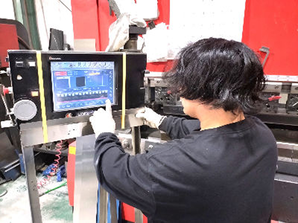 ステンレス加工機を操作するスタッフ